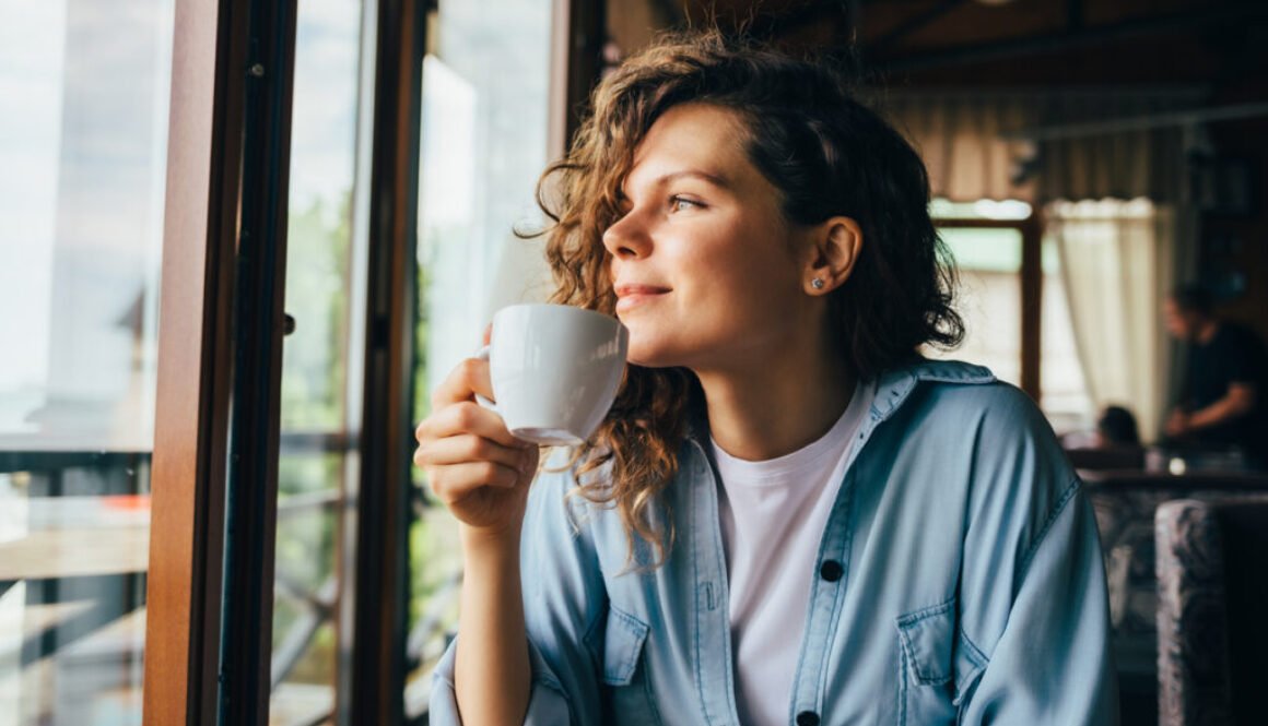 Smiling calm young woman drinking coffee