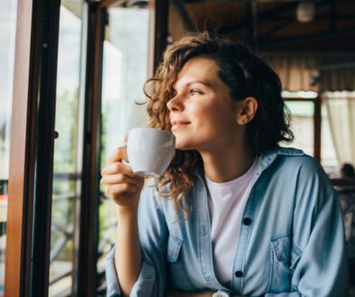 Smiling calm young woman drinking coffee